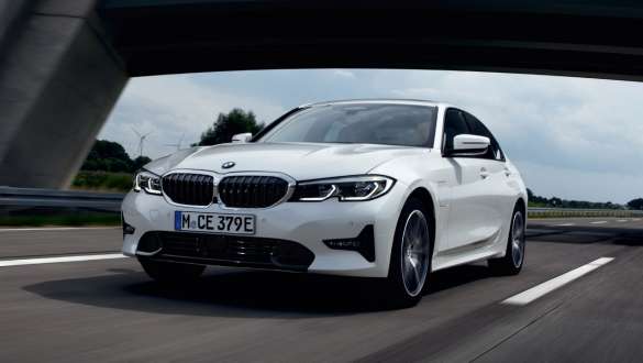 Visão frontal 3/4 do veículo plug-in híbrido BMW Série 3 Sedan 2021 G20, dirigindo Visão frontal 3/4 do veículo plug-in híbrido BMW Série 3 Sedan 2021 G20, dirigindo na rua