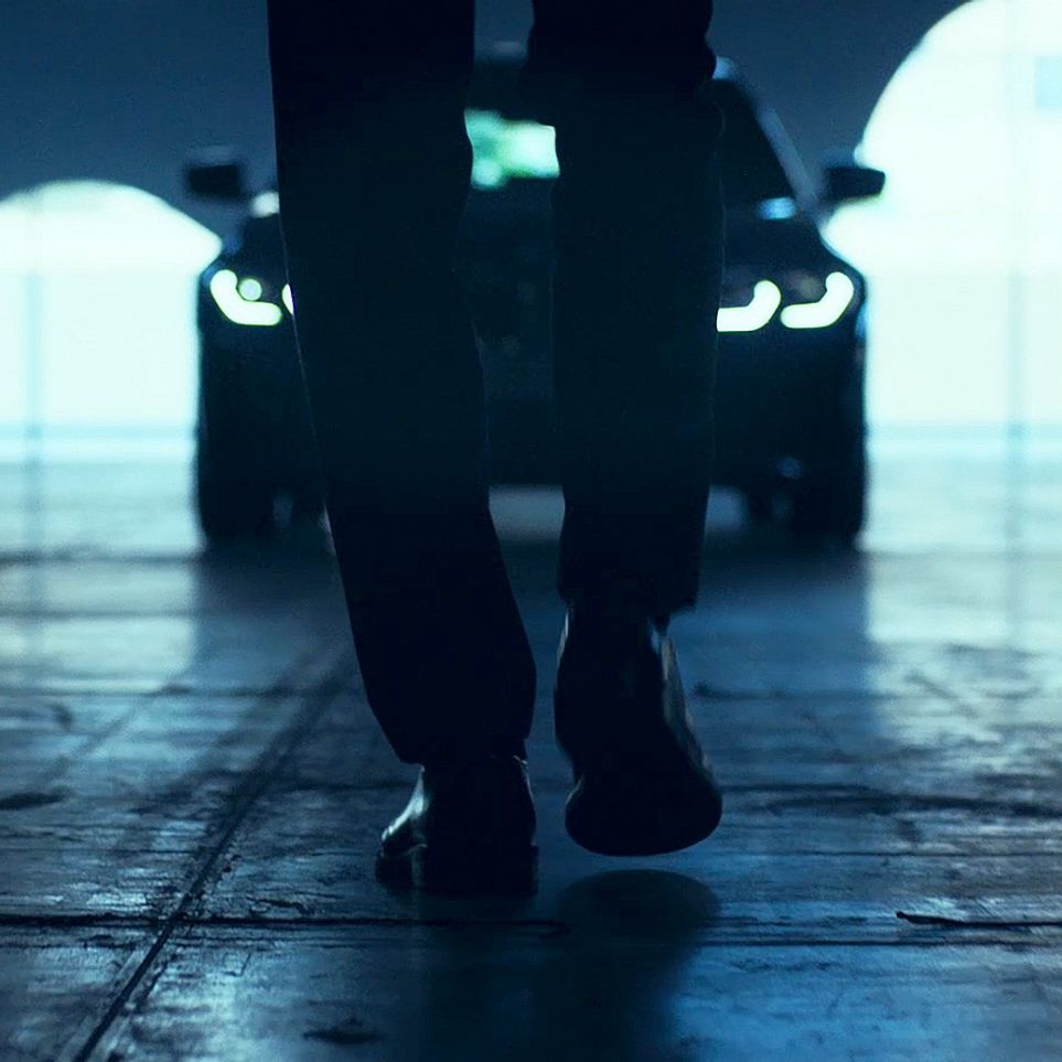 BMW Série 3 Sedã, Vista Frontal. Vista de trás de um homem caminhando em frente do BMW Série 3 Sedã no asfalto.