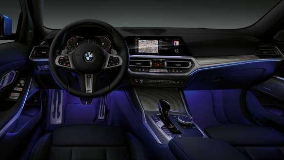 BMW Série 3 Sedã, luz Ambiente. Vista frontal da cabine do motorista do BMW Série 3 Sedã com espaço para as pernas iluminado por luz ambiente azul.