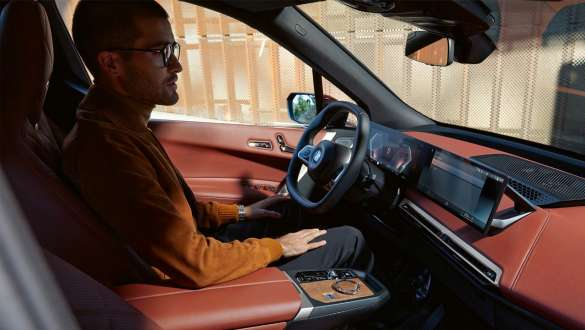 Um homem em seu BMW, vista lateral do passageiro Um homem em seu BMW no banco do motorista, vista lateral do passageiro