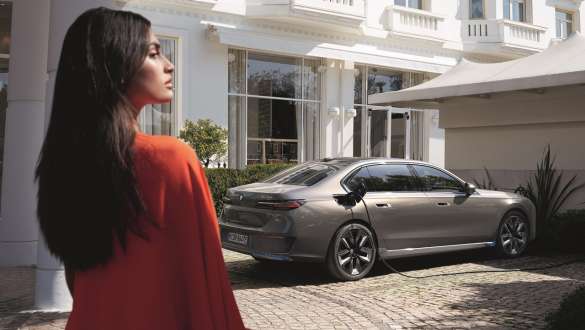 Uma mulher em frente de um BMW estacionado Uma mulher em frente de um BMW estacionado em um posto de carregamento