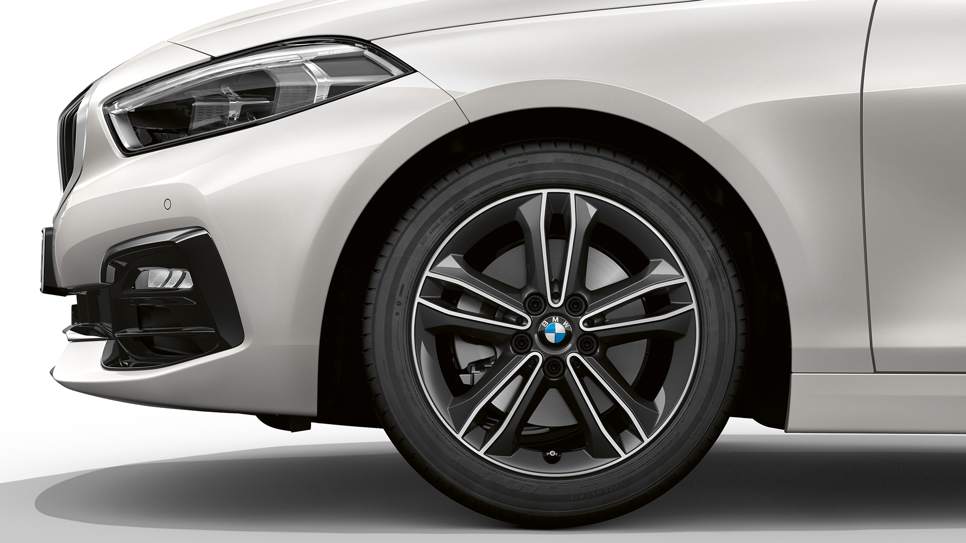 Rodas de liga leve de 17 polegadas de raio duplo, estilo 549. BMW Série 1 Modelo Sport Line na tonalidade Mineral White metálico, vista lateral da dianteira com rodas de liga leve de 17 polegadas de raio duplo, estilo 549.
