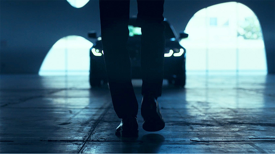 Dianteira do BMW Série 3 Sedã (G20). Visão traseira de um homem andando no asfalto à frente do BMW Série 3 Sedã (G20).