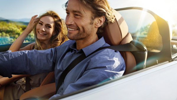 Casal sorridente aproveitando em um dia de sol o conforto do BMW Série 4 Cabrio proporcionado pelo defletor de vento Casal sorridente aproveitando em um dia de sol o conforto do BMW Série 4 Cabrio proporcionado pelo defletor de vento
