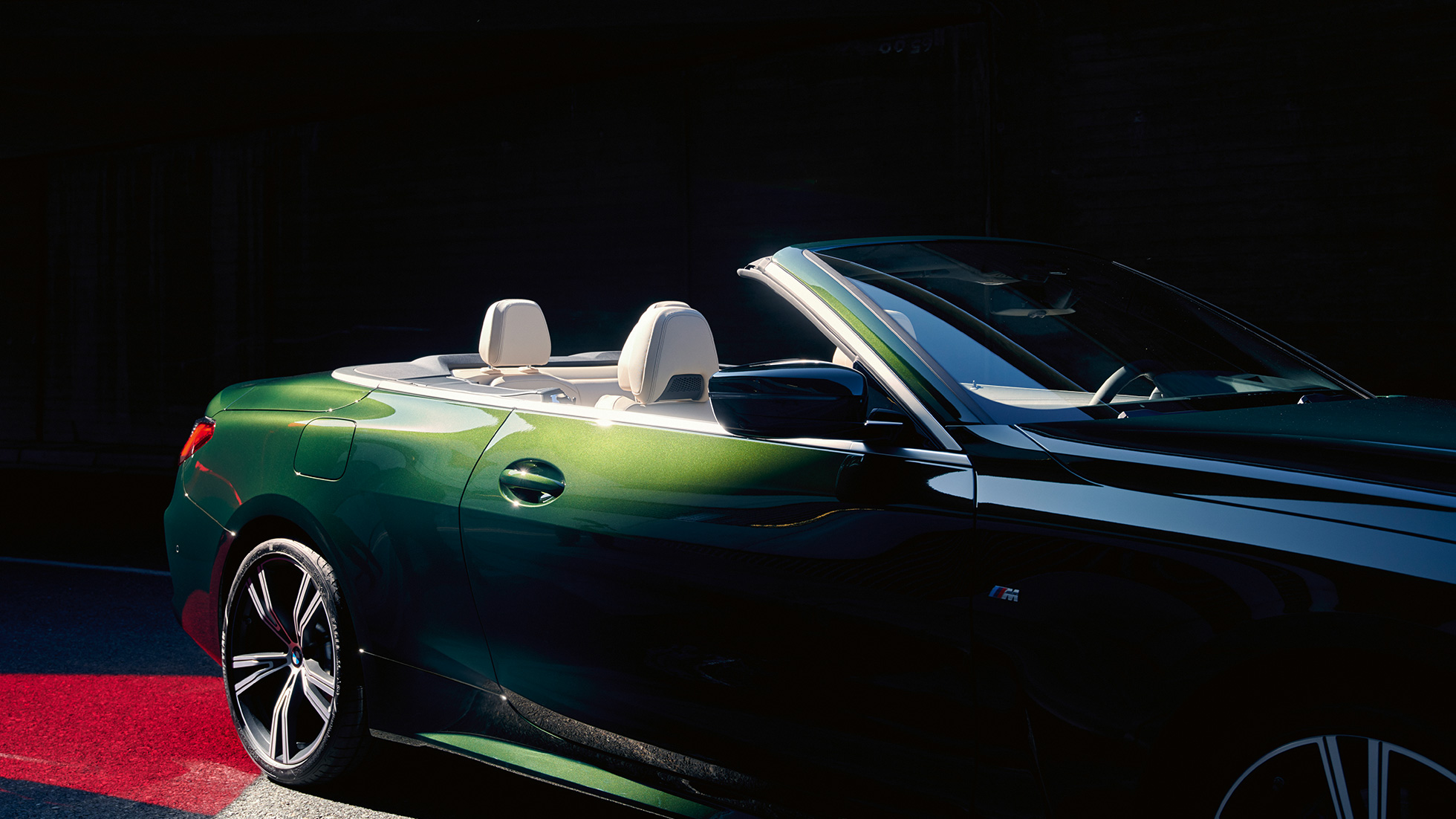 Vista frontal a três quartos do BMW Série 4 Cabrio em movimento. BMW Série 4 Cabrio cor exterior verde Sanremo metalizada, vista traseira a três quartos em movimento.