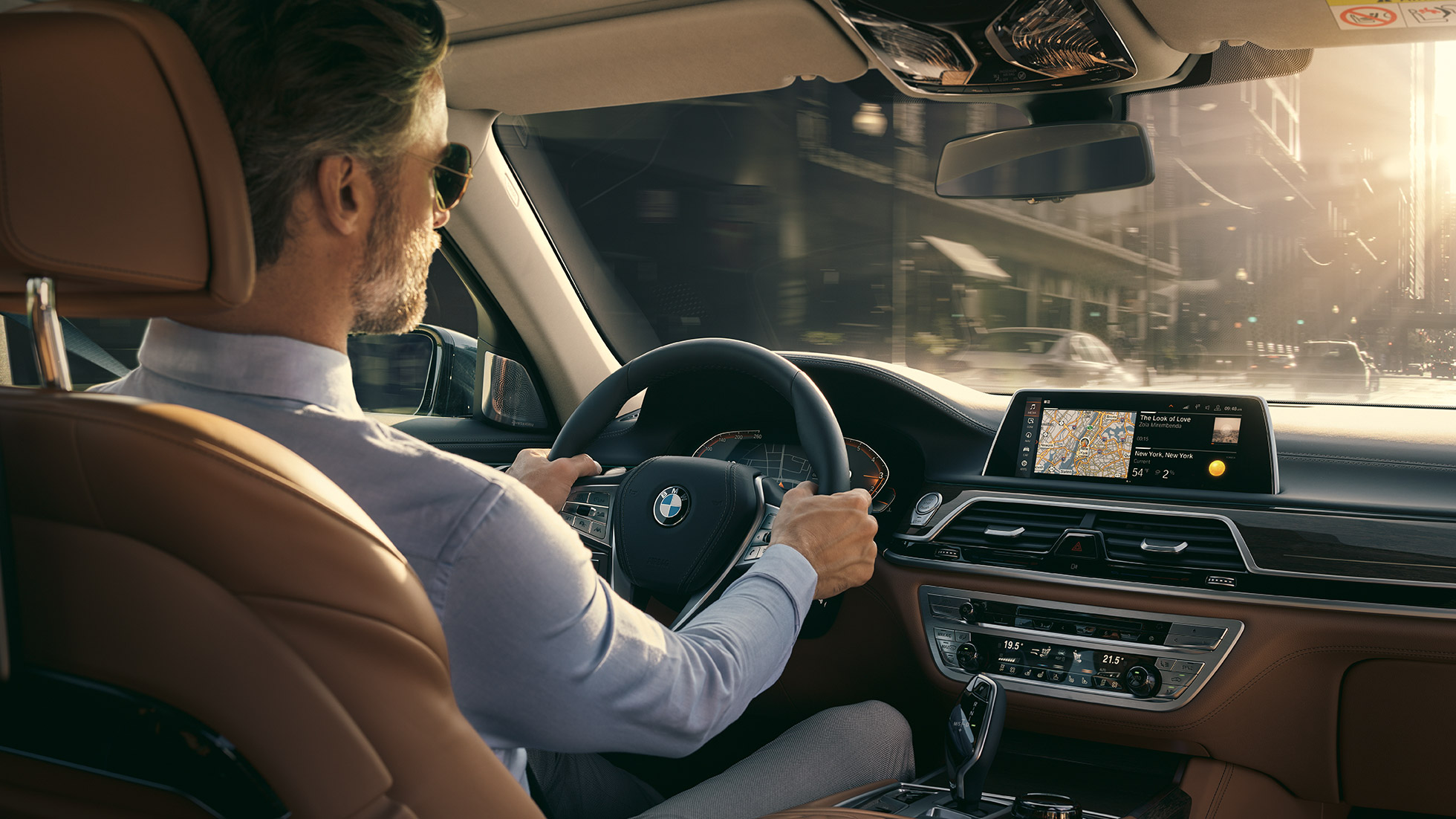 As características de conectividade do BMW Série 7 Sedan BMW Série 7 Sedan: um homem se senta em um BMW, utilizando os recursos de conectividade