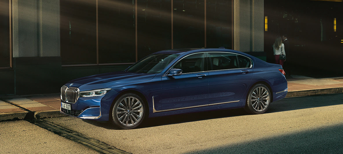 Vista lateral do BMW Série 7 Sedan Individual Vista lateral do BMW Série 7 Sedan Individual na tonalidade vermelha em frente a um cenário urbano