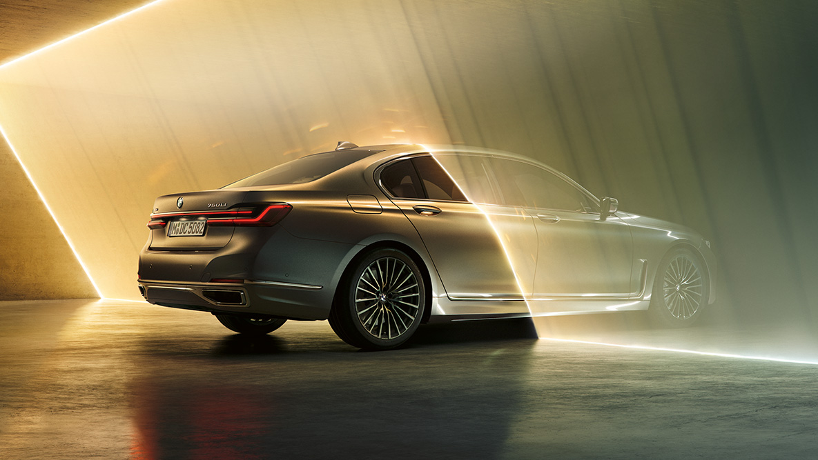 BMW Série 7 Sedan na tonalidade Bernina Grey Visão traseira 3/4 do BMW Série 7 Sedan na tonalidade Bernina Grey, cercado por um feixe de luz
