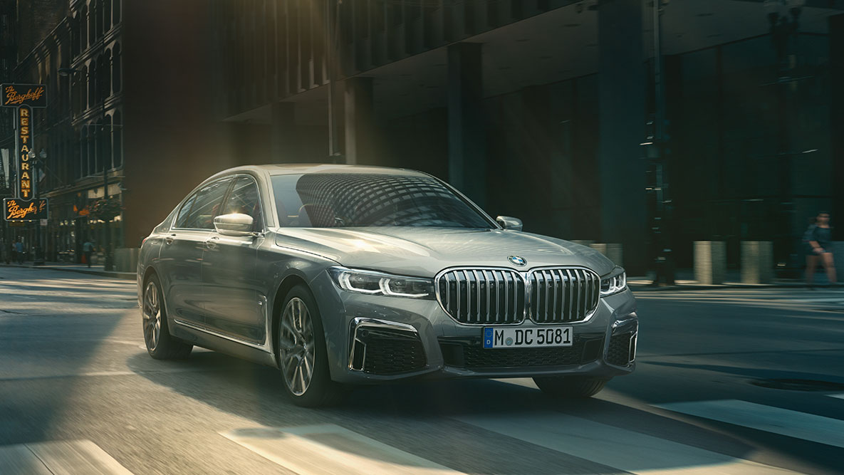 Driving Assistant Professional: vista frontal 3/4 do BMW Série 7 Sedan dirigindo em frente a um panorama urbano Driving Assistant Professional do BMW Série 7 Sedan