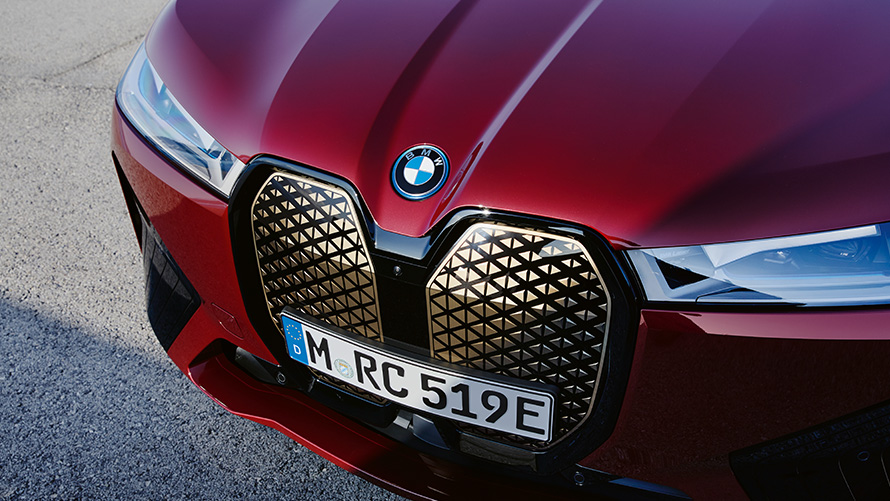 Tecnologia embutida no SUV elétrico BMW iX, i20 e no BMW iX xDrive50, Vista frontal do SUV elétrico BMW iX, i20, 2021, e o BMW iX xDrive50, com exterior na tonalidade Aventurin Red e a grade curva da BMW, uma forma de tecnologia embutida