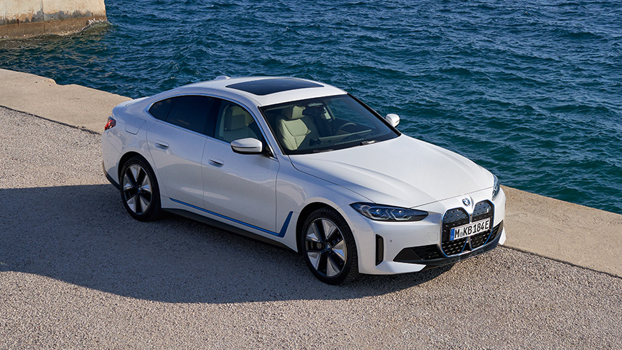 Vista dianteira 3/4 do BMW i4 eDrive40 G26 2021, em um cais. Vista dianteira 3/4 do BMW i4 eDrive40 G26 2021, pintura Mineral White, em um cais.