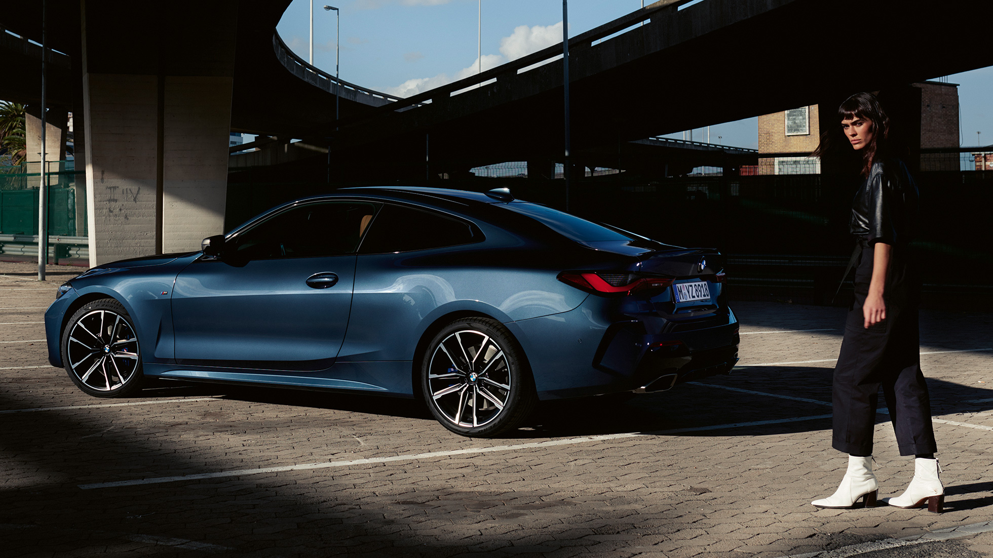 Vista traseira 3/4 do BMW M440i xDrive Coupé, G22, 2020 Vista traseira 3/4 do BMW M440i xDrive Coupé, com exterior na tonalidade Arctic Race Blue metálico, G22, 2020, com uma modelo