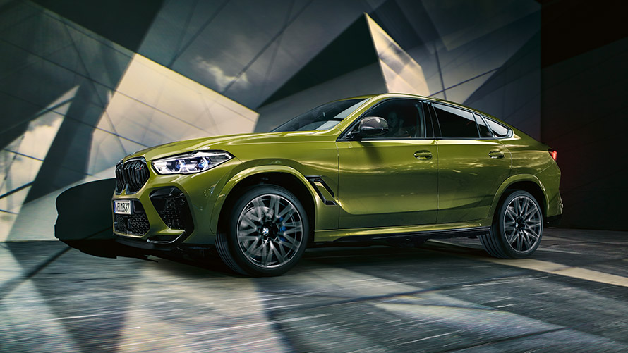 BMW X6 M F96 visão lateral. BMW M Series BMW X6 M F96 visto de lado, parado em construção de vidro.