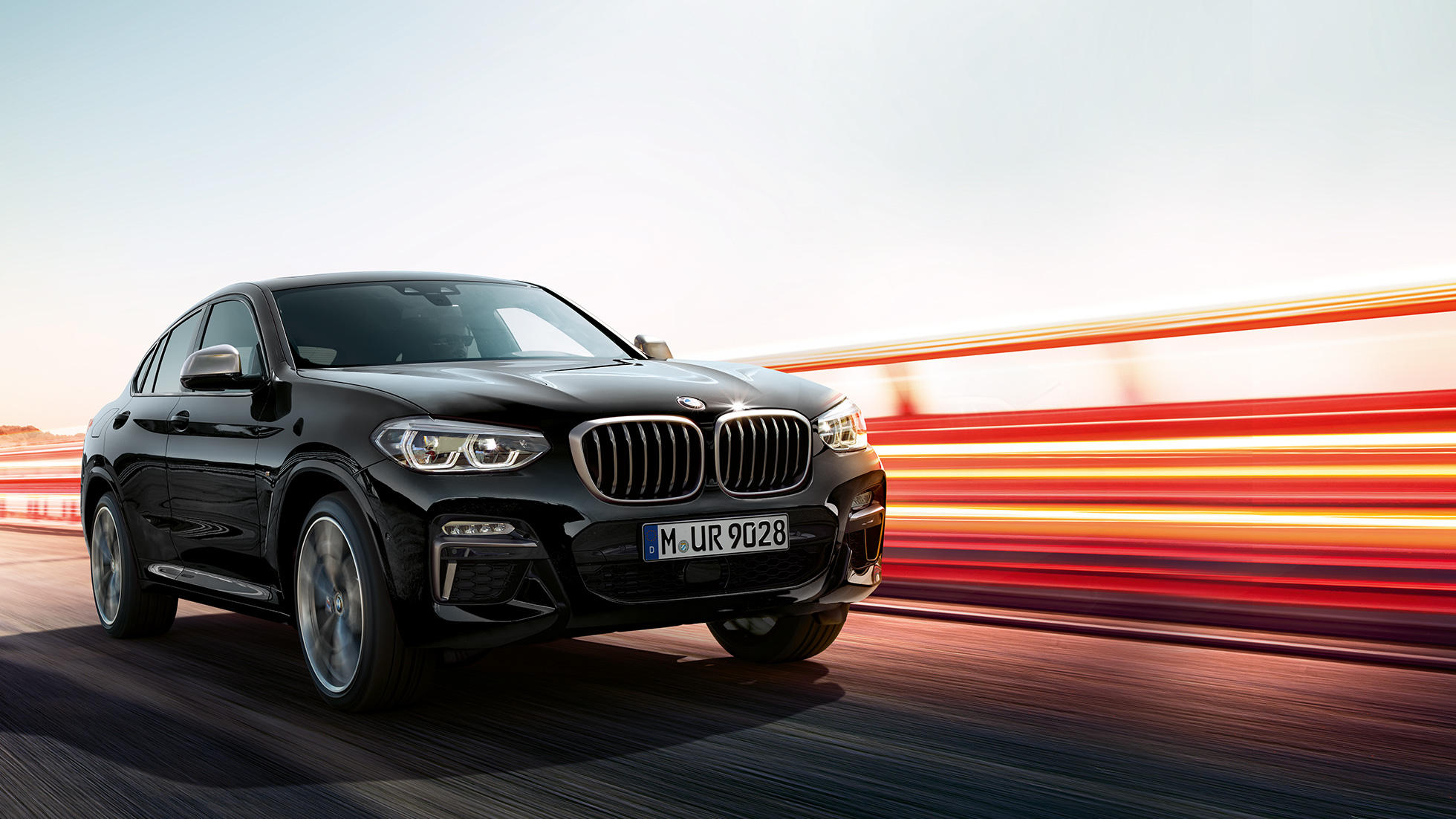 BMW X4 M40i, visão traseira de três quartos. BMW X4 M40i em preto safira metálico, direção, exterior, visão traseira de três quartos com tiras de luz.