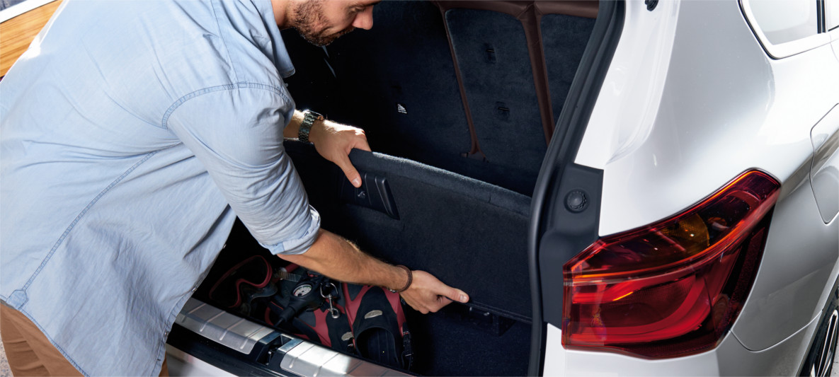 Homem fechando o primeiro nível da tampa flexível do compartimento inferior do porta malas do BMW X1 2020 Homem fechando o primeiro nível da tampa flexível do compartimento inferior do porta malas do BMW X1 2020