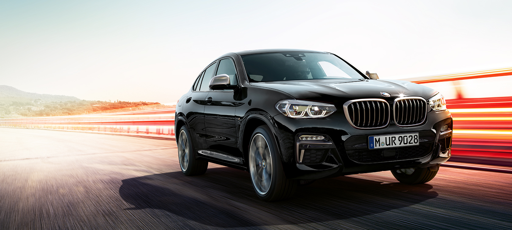 BMW X4 2020 / 2021 Preto andando rapidamente por uma estrada, visão frontal de três quartos BMW X4 2020 / 2021 Preto andando rapidamente por uma estrada, visão frontal de três quartos