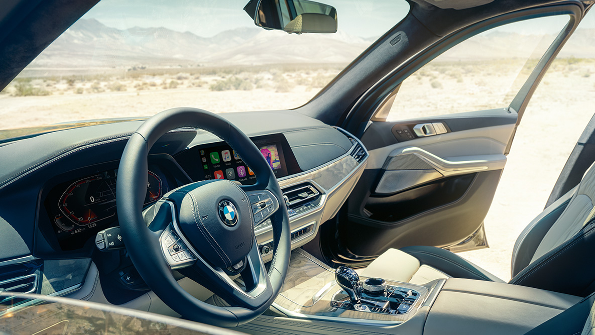 Interior do BMW X7 Interior do BMW X7: vista tomada de fora em direção à primeira fila de bancos, mostrando o volante da direção, o painel de instrumentos e os bancos de couro
