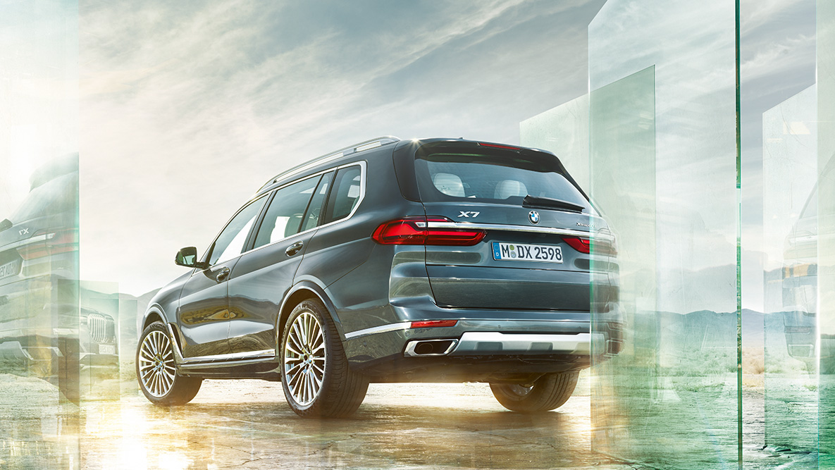 O BMW X7 - Conforto e Dinâmica ao Dirigir BMW X7 em vista traseira a 45 graus à frente de um fundo abstrato