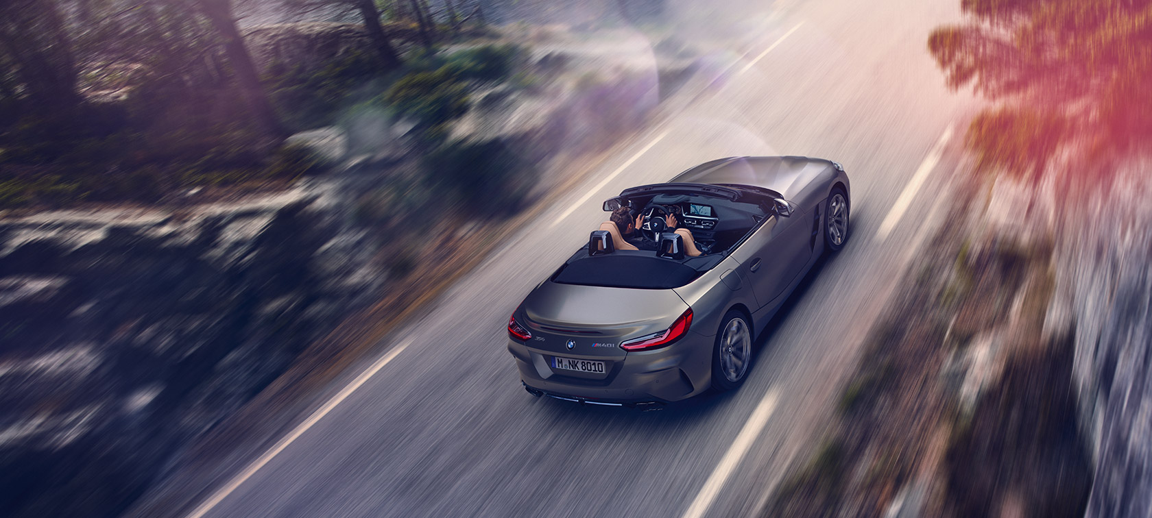 Visão aérea do BMW Z4 Roadster M40i viajando com velocidade de capota aberta em meio à natureza Visão aérea do BMW Z4 Roadster M40i viajando com velocidade de capota aberta em meio à natureza