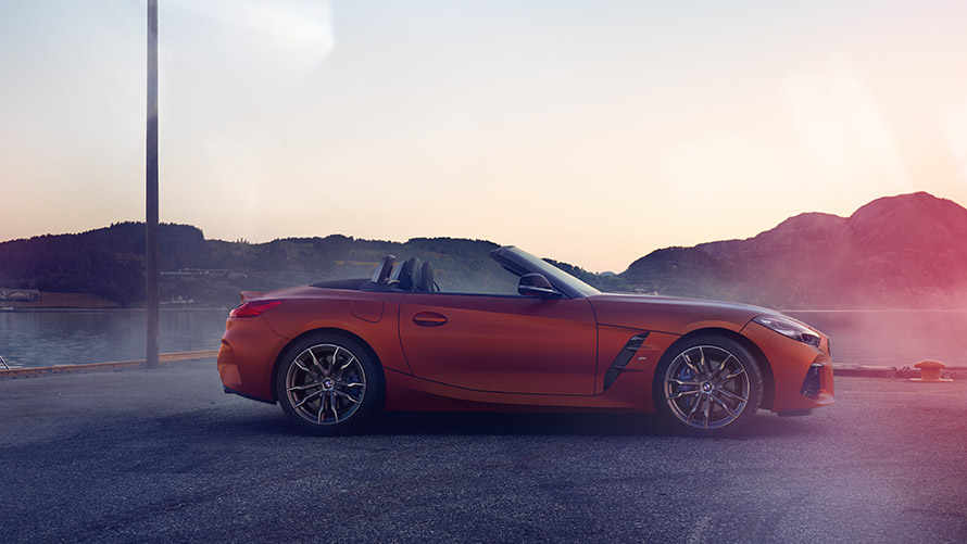 Vista lateral de um BMW Z4 First Edition na cor laranja Vista lateral de um BMW Z4 First Edition na cor laranja, frente a um panorama de montanha