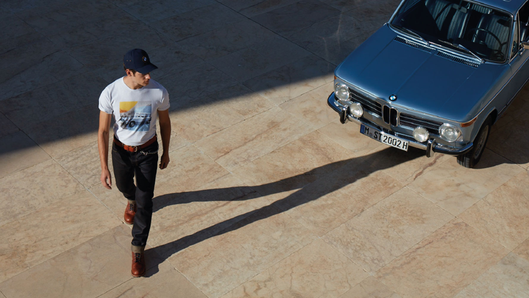 Um homem vestindo uma camiseta masculina BMW Classic é mostrado admirando um modelo clássico da BMW. Um homem vestindo uma camiseta masculina BMW Classic é mostrado admirando um modelo clássico da BMW.