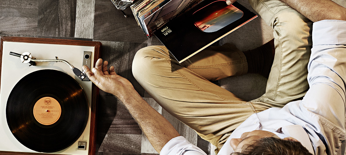 Homem escutando música em sua vitrola com discos de vinil Homem escutando música em sua vitrola com discos de vinil