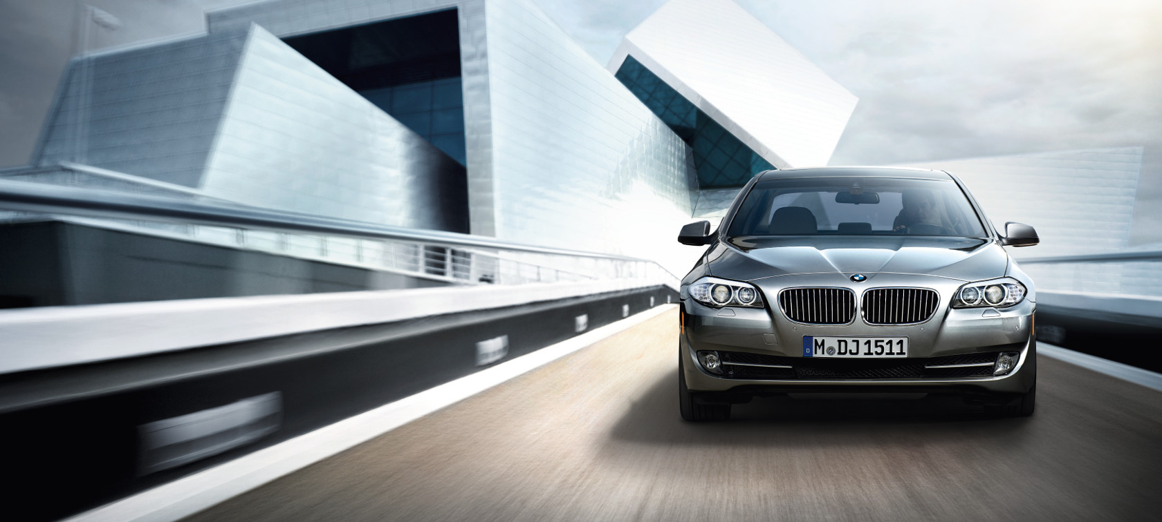 Veículo BMW viajando por moderna cidade - visão frontal Veículo BMW viajando por moderna cidade - visão frontal