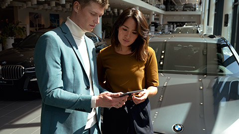 Local de consulta BMW com duas pessoas. Local de consulta BMW com duas pessoas em frente a um veículo BMW.