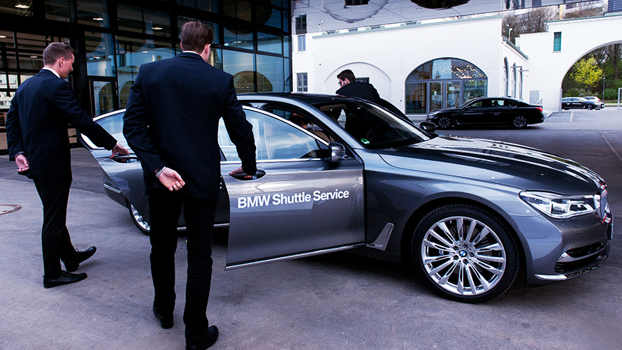 Dois homens recepcionando convidados abrindo as portas de um BMW Série 7 para convidados que acabaram de chegar Dois homens recepcionando convidados abrindo as portas de um BMW Série 7 para convidados que acabaram de chegar