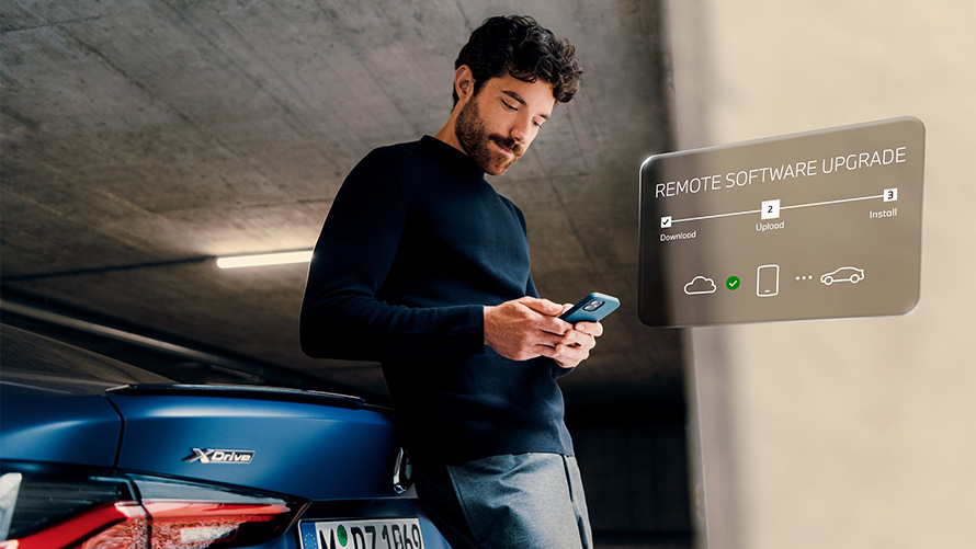 Atualização Remota de Software. Um homem se debruça sobre a traseira de um BMW e olha para o seu smartphone