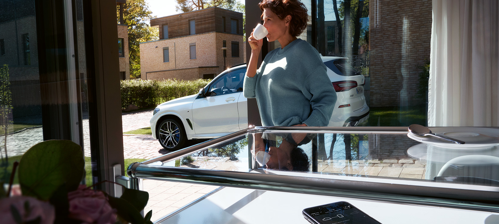 Atualização remota de software BMW Mulher a beber de um copo enquanto a atualização remota de software atualiza o seu BMW X5