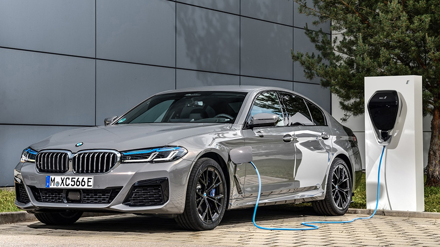 Veículo híbrido BMW realizando a Atualização Remota de Software na estação de carregamento Vista frontal 3/4 do veículo híbrido BMW realizando a Atualização Remota de Software na estação de carregamento