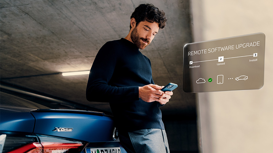 Homem apoiado na traseira do BMW e olhando seu smartphone Atualização Remota de Software Homem apoiado na traseira do BMW e olhando seu smartphone