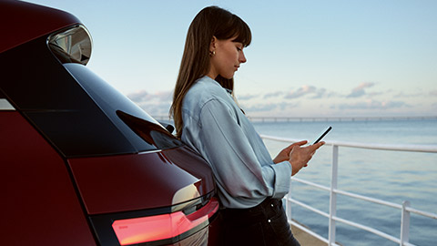 Mulher utiliza o My BMW App num smartphone Mulher utiliza o My BMW App através do BMW ConnectedDrive no smartphone