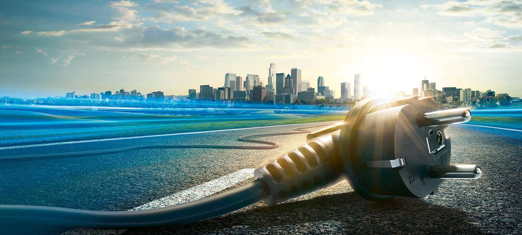 BMW eDrive simbolizado por tomada de energia sobre asfalto com cidade ao fundo. BMW eDrive simbolizado por tomada de energia sobre asfalto com cidade ao fundo.