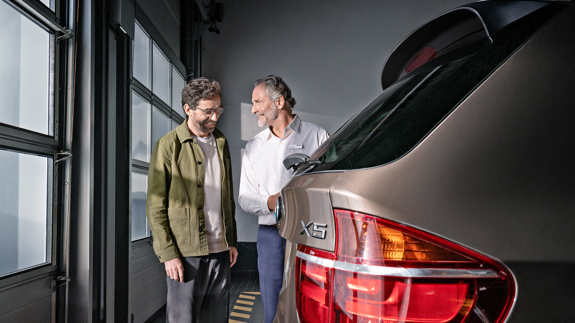 BMW Fidelidade Cliente homem em atendimento por empresa parceira BMW, analisa farol do X5.