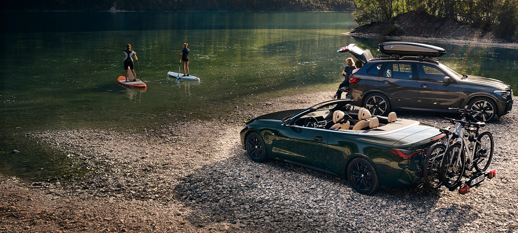 Veículos BMW em frente a um lago e uma paisagem verde Veículos BMW em frente a um lago e uma paisagem verde