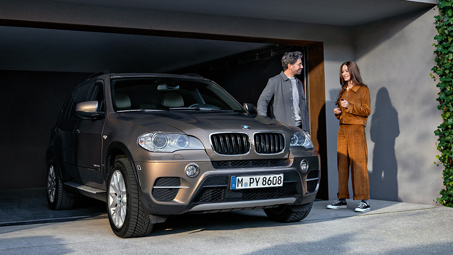 BMW em frente a uma garagem, com modelos Programa BMW Fidelidade, um BMW em frente a uma garagem, com modelos