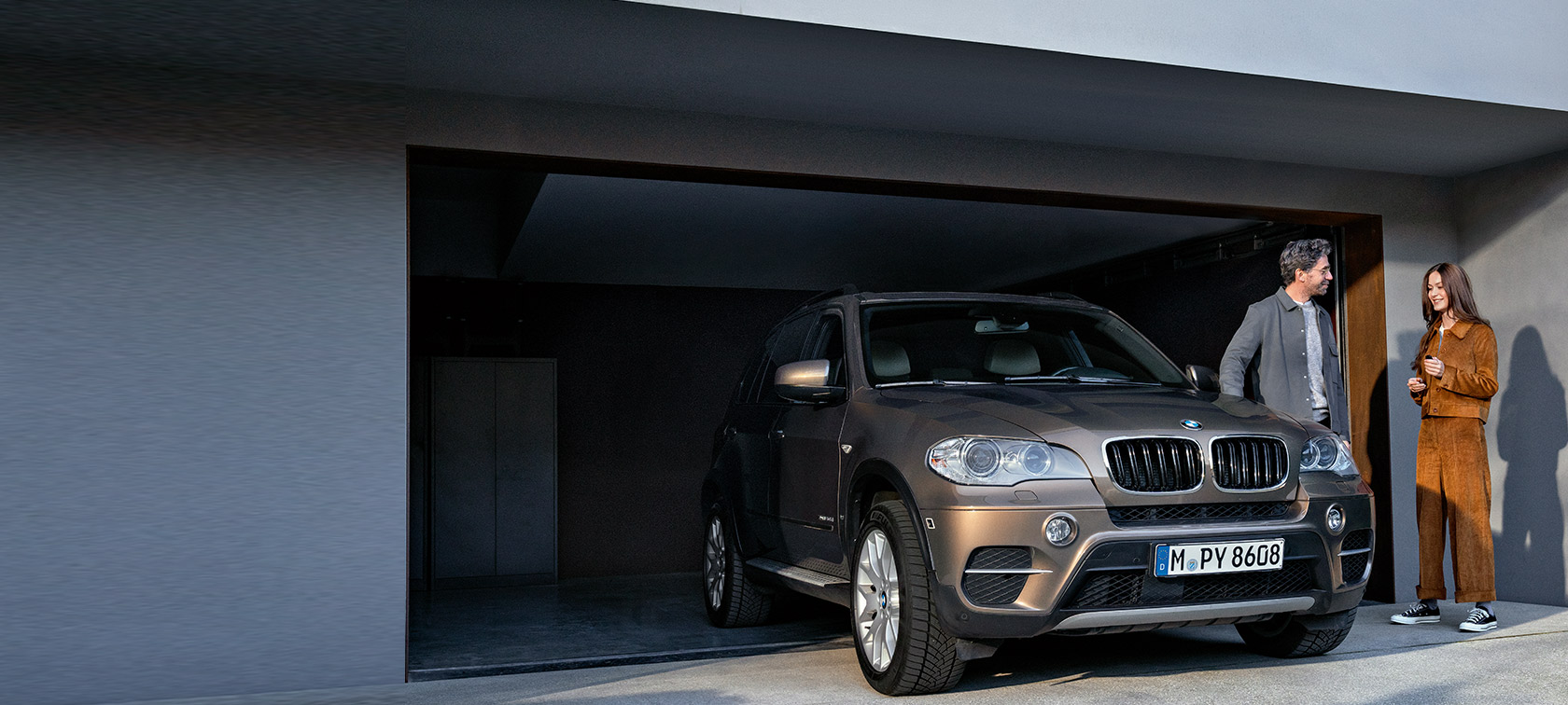 Programa BMW Fidelidade Programa BMW Fidelidade, um homem e uma mulher em frente a uma garagem com o BMW X5