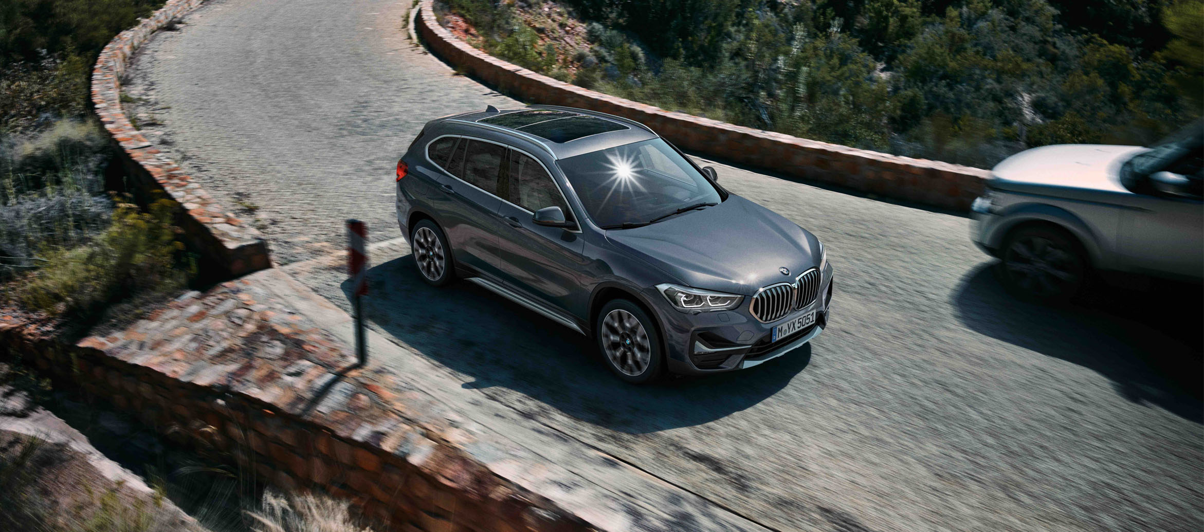 BMW X1 2020 Cinza fazendo uma curva, vista aérea da lateral BMW X1 2020 Cinza fazendo uma curva, vista aérea da lateral