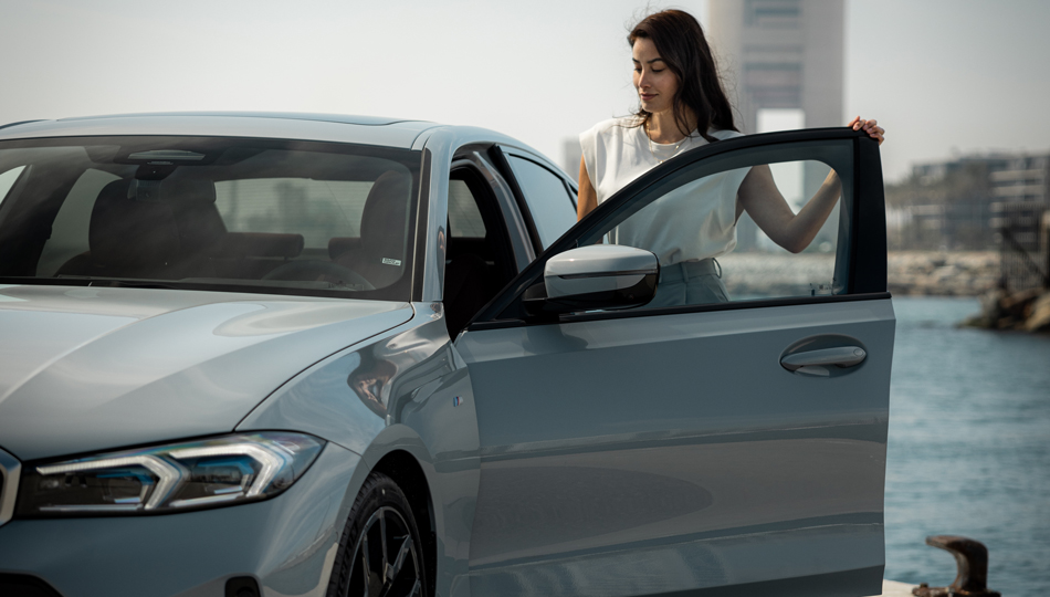 Homem inclinando-se sobre um BMW, em frente a um cenário de montanha Acessórios primavera/verão BMW, mostrando um homem inclinando-se sobre um BMW, em frente a um cenário de montanha