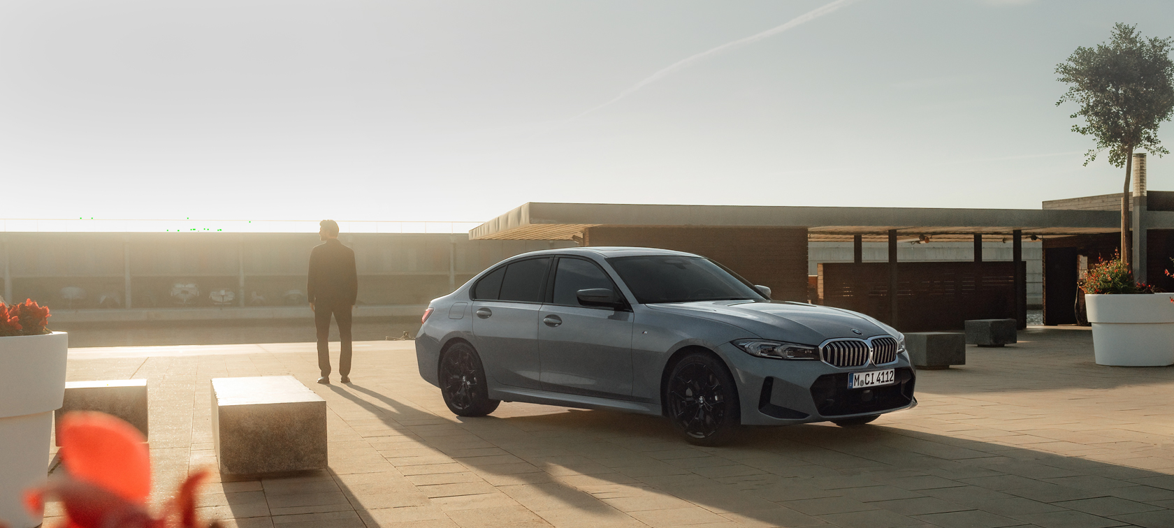  Carro com seguro BMW está com a porta aberta e mulher sentada com mão no volante.