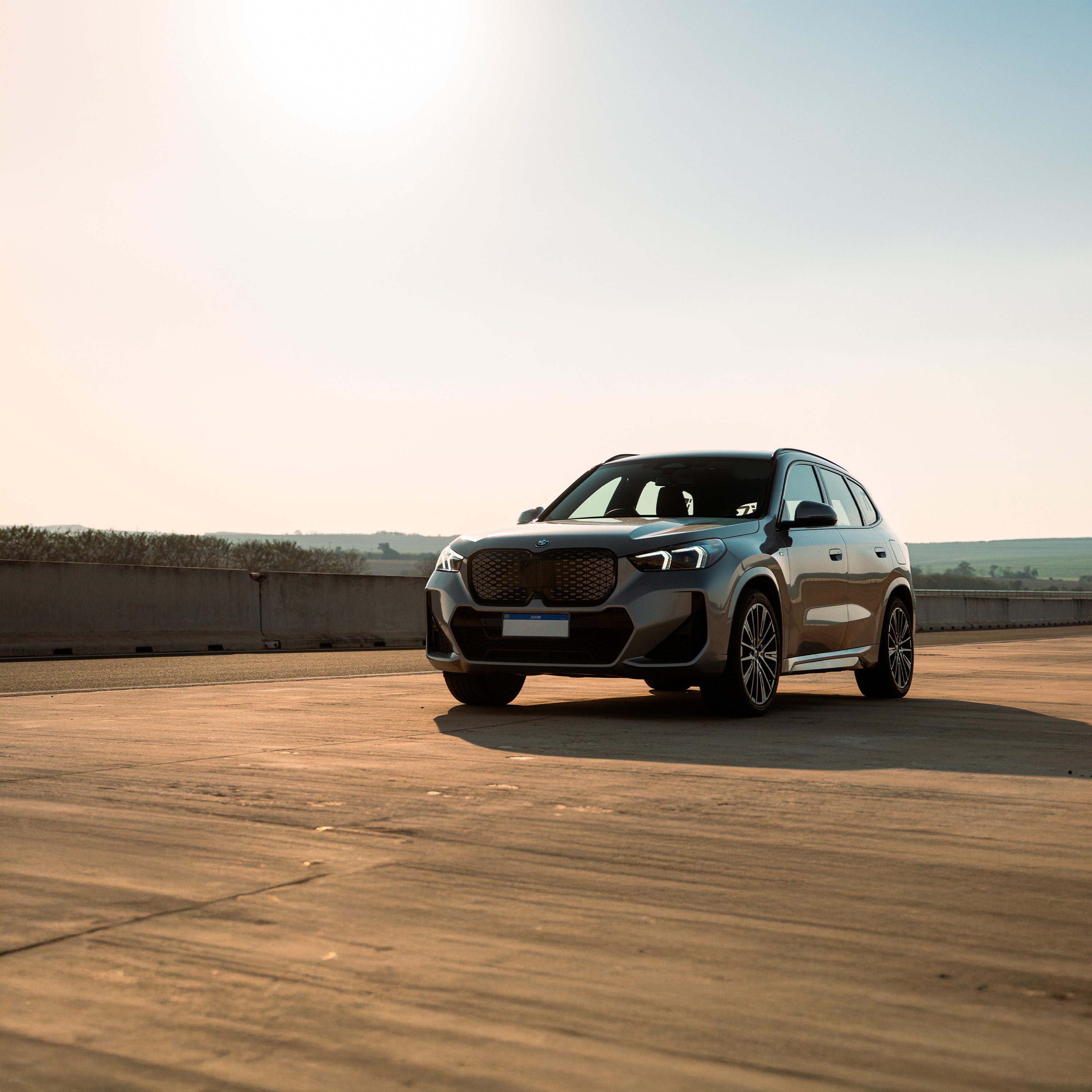 BMW iXi Premium Selection passando em rua de bairro. 